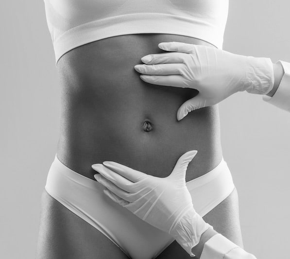 Cropped of plastic surgeon hands checking afro woman belly before beauty procedure, liposuction concept